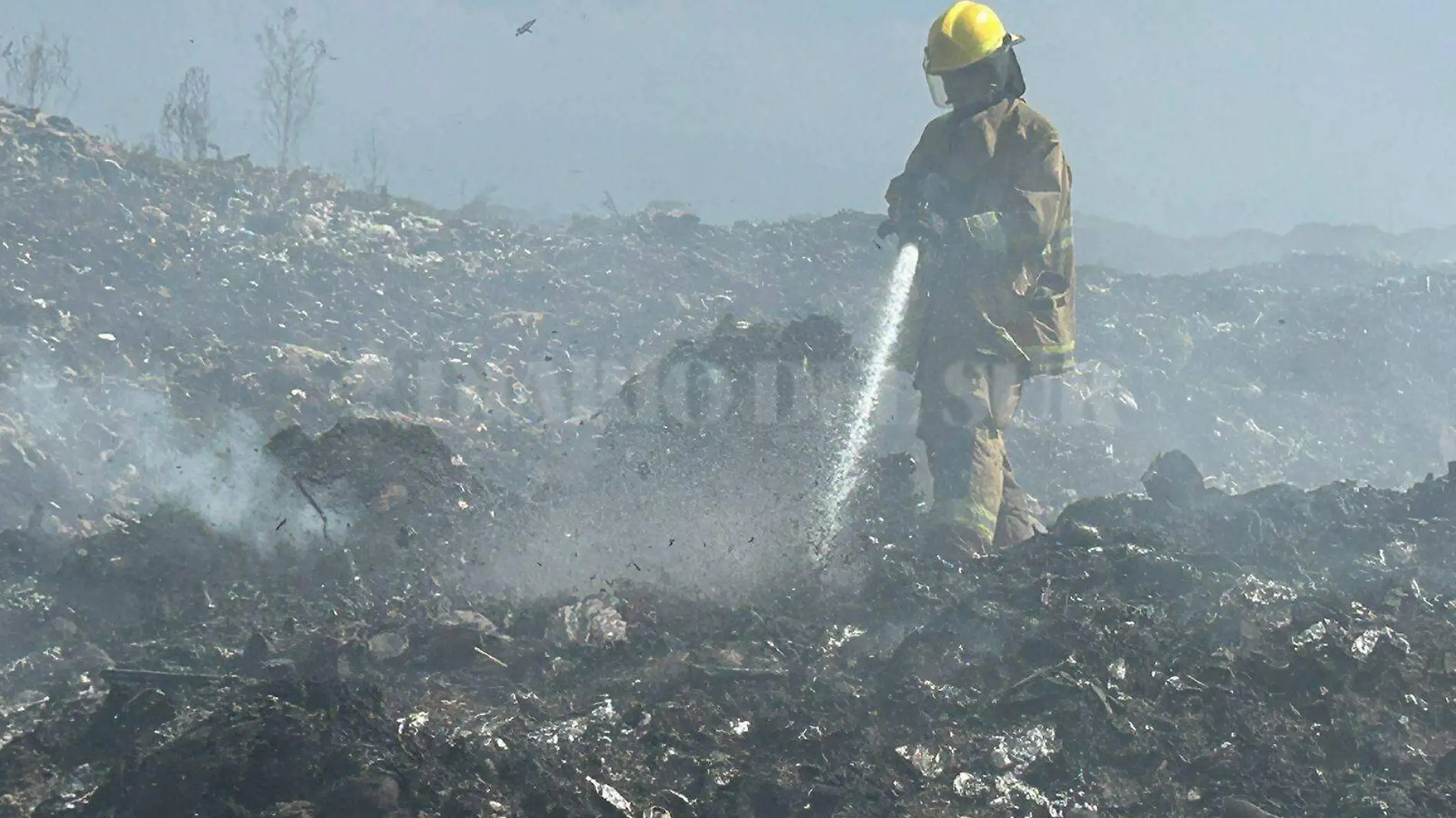 bombero apagando incendio en basurero